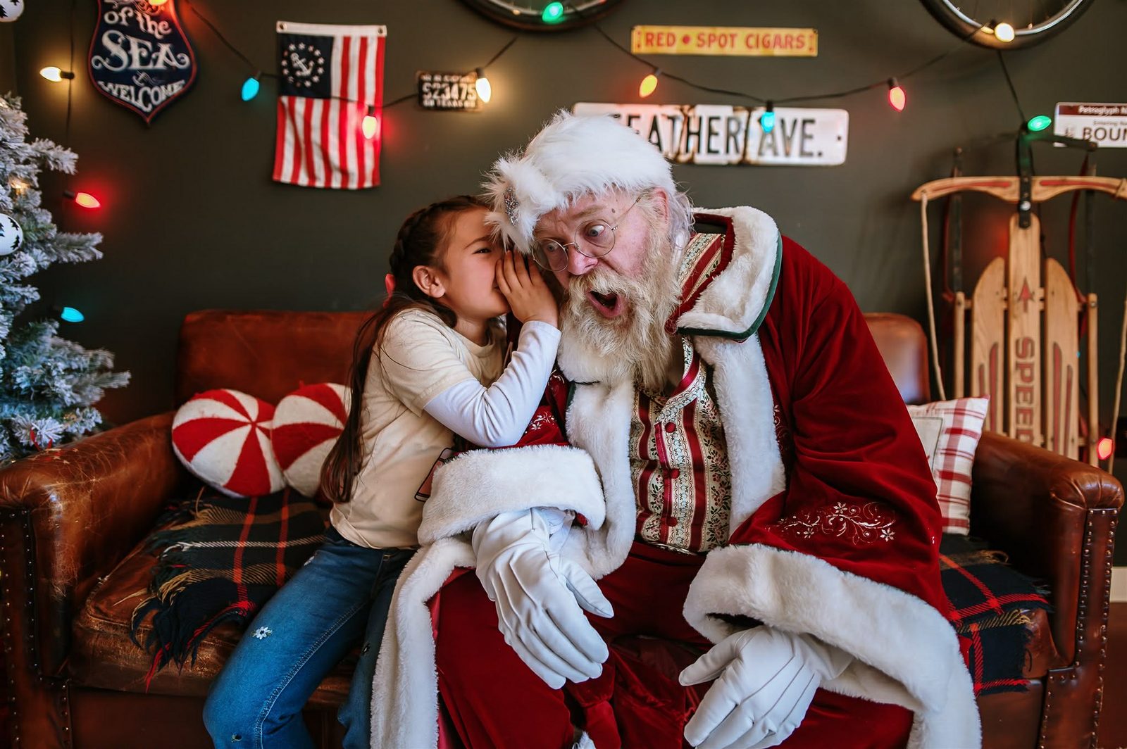 A child whispers a secret to a delighted Santa Michael