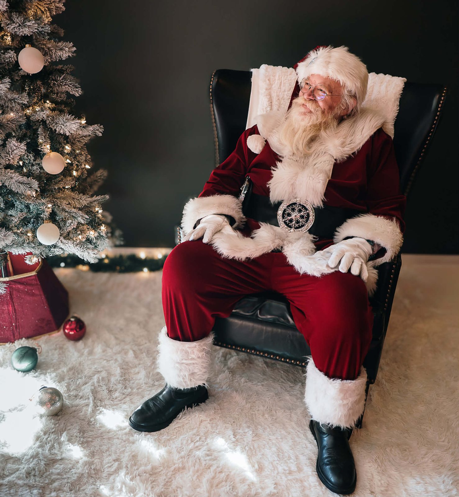 Santa Michael resting in a chair by a Christmas tree